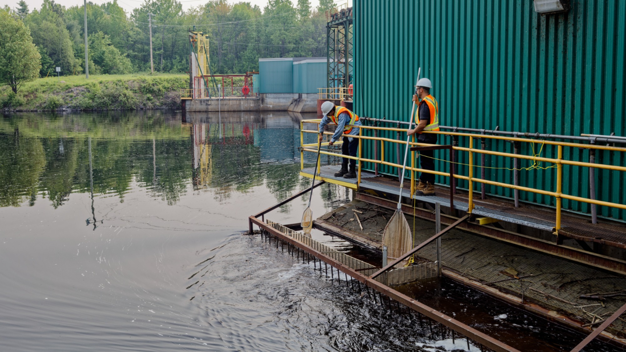 Deux techniciens en train d’utiliser une puise dans un bassin